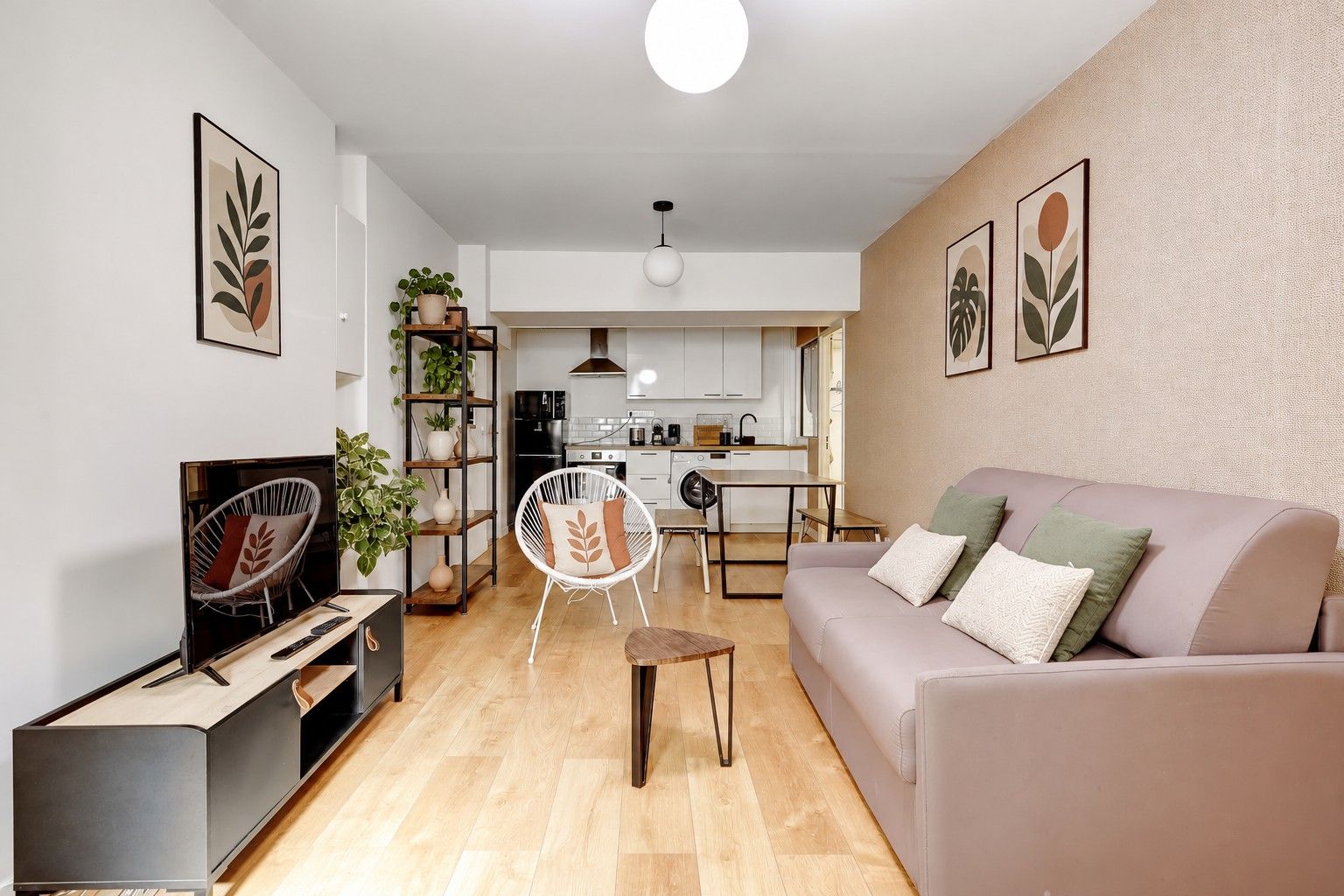 A modern living room with a sofa, a TV, a dining area, and a kitchen in the background.