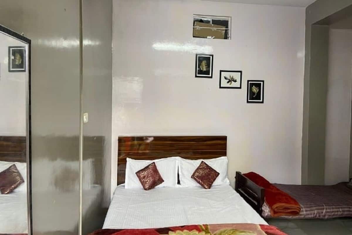 A bedroom with a bed, a bedside table, a mirror, and a window.
