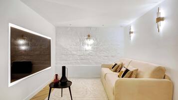 Una sala de estar moderna con un ventanal grande, un sofá, una mesita y un aplique de pared.