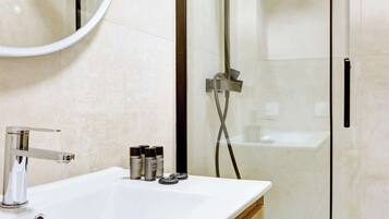 Un baño moderno con lavamanos blanco, grifo cromado y cabina de ducha de vidrio.