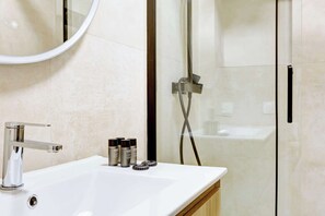 Ein modernes Badezimmer mit einem weißen Waschbecken, einem Chrom-Wasserhahn und einer Duschkabine aus Glas.