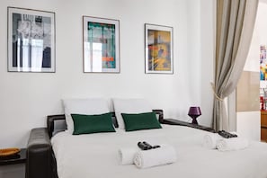 A hotel room with a bed, pillows, a nightstand, and framed pictures on the wall.