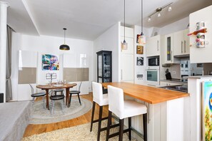 A modern kitchen with white cabinets, a wooden island, and pendant lighting.