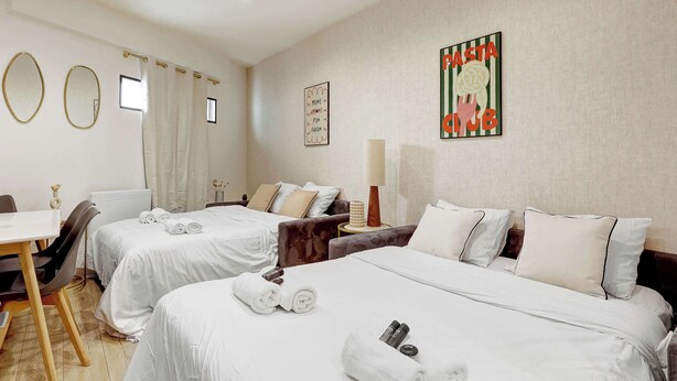 Camera d'albergo con due letti, una scrivania, una sedia, una lampada e un quadro appeso al muro.