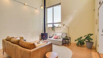 Tunnelmallinen olohuone, jossa on ruskea nahkasohva, pyöreä puujakkara, harmaa sohva, jossa on kasvi, ja musta puukamiina.