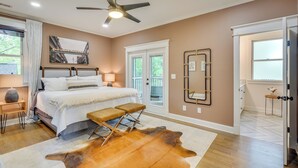 Une chambre à coucher avec un lit, des tables de chevet, un ventilateur de plafond, une fenêtre et une porte.