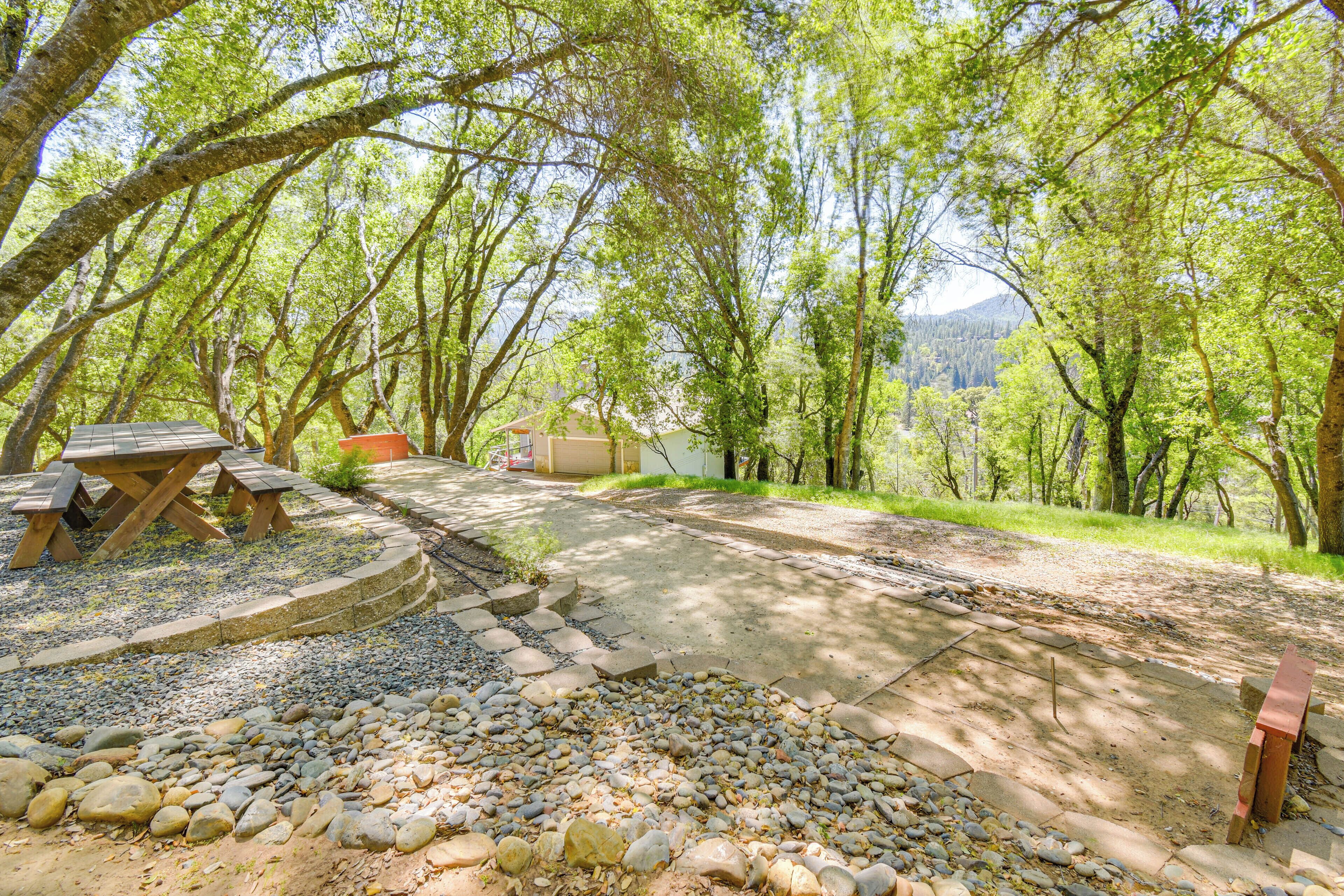 A picnic area with benches and a picnic table surrounded by trees.
