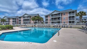 A swimming pool with a 4x6 feet sign, surrounded by multi-story buildings with balconies and palm trees.