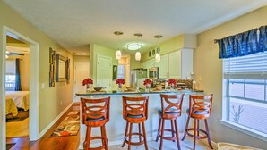 A kitchen with a central island, bar stools, and a window with blinds.