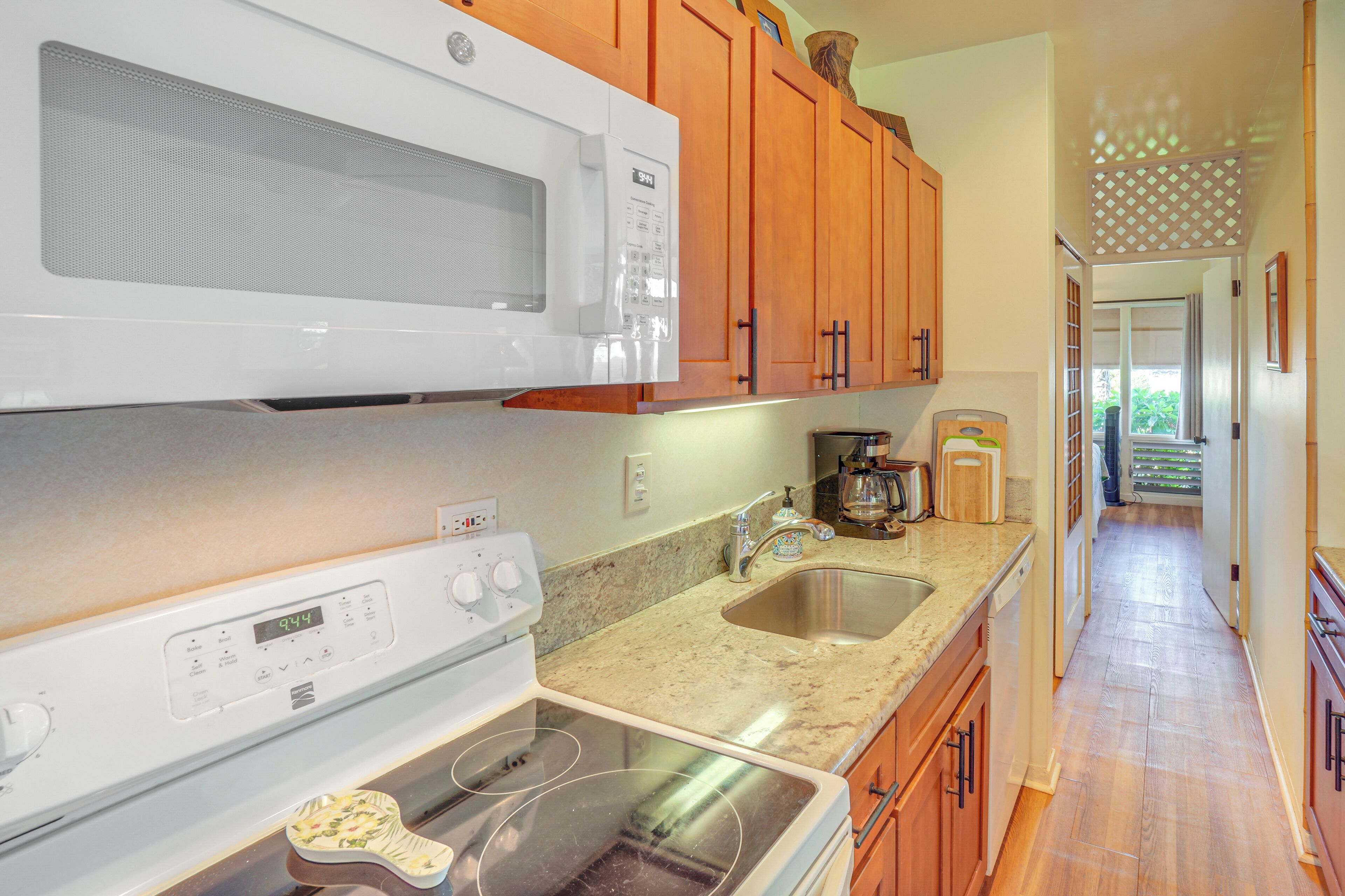 A kitchen with a microwave, stove, sink, and wooden cabinets.