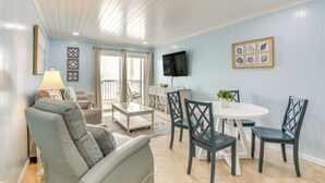 A living room with a sofa, chairs, a coffee table, a TV, and a dining table with chairs. - 1 Mi to Barefoot Landing: Condo w/ Pool Access! (North Myrtle Beach)