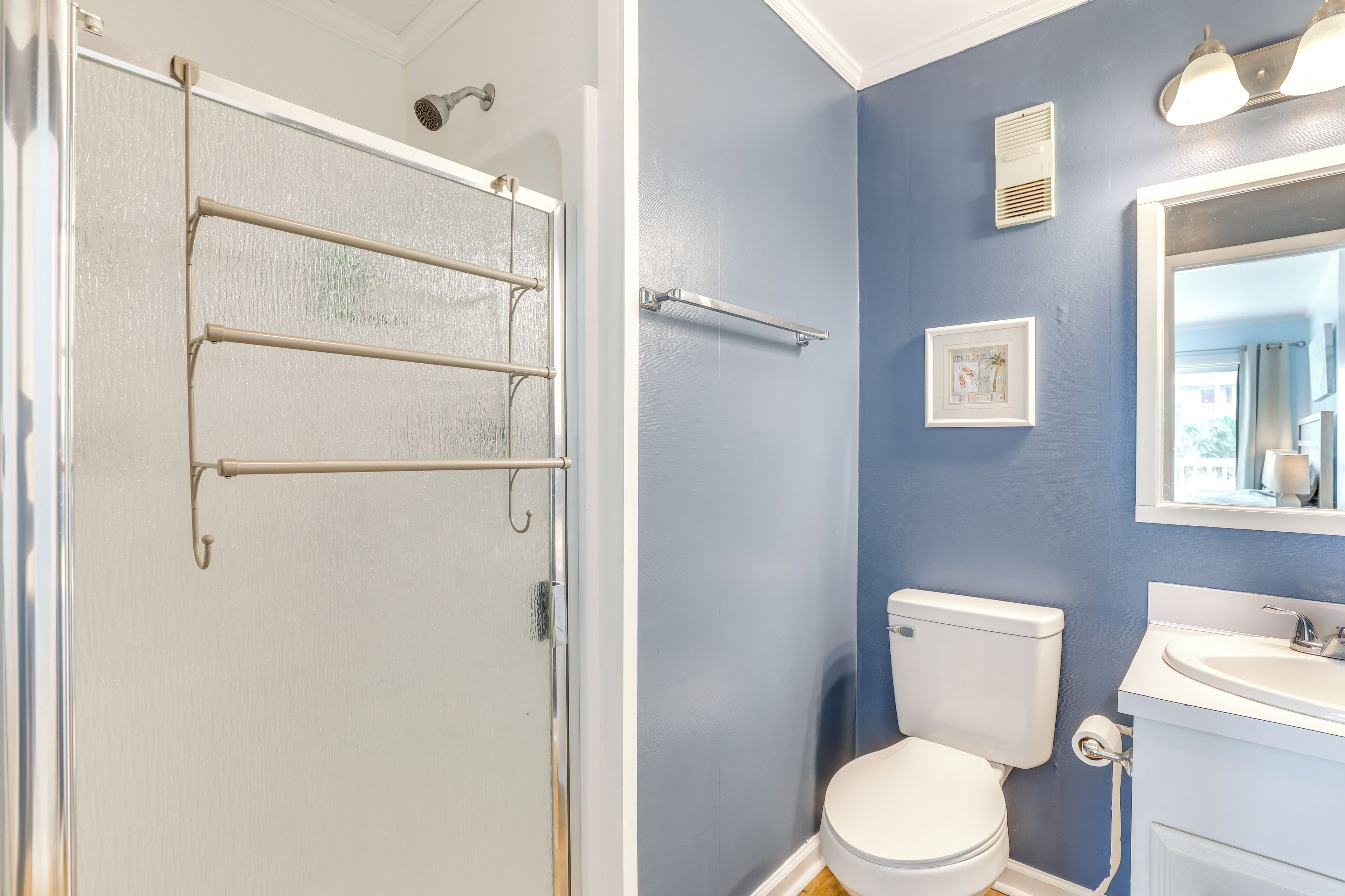 A bathroom with a white toilet, a sink, and a shower with a glass door.