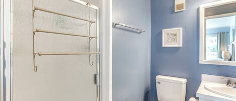 A bathroom with a white toilet, a sink, and a shower with a glass door.