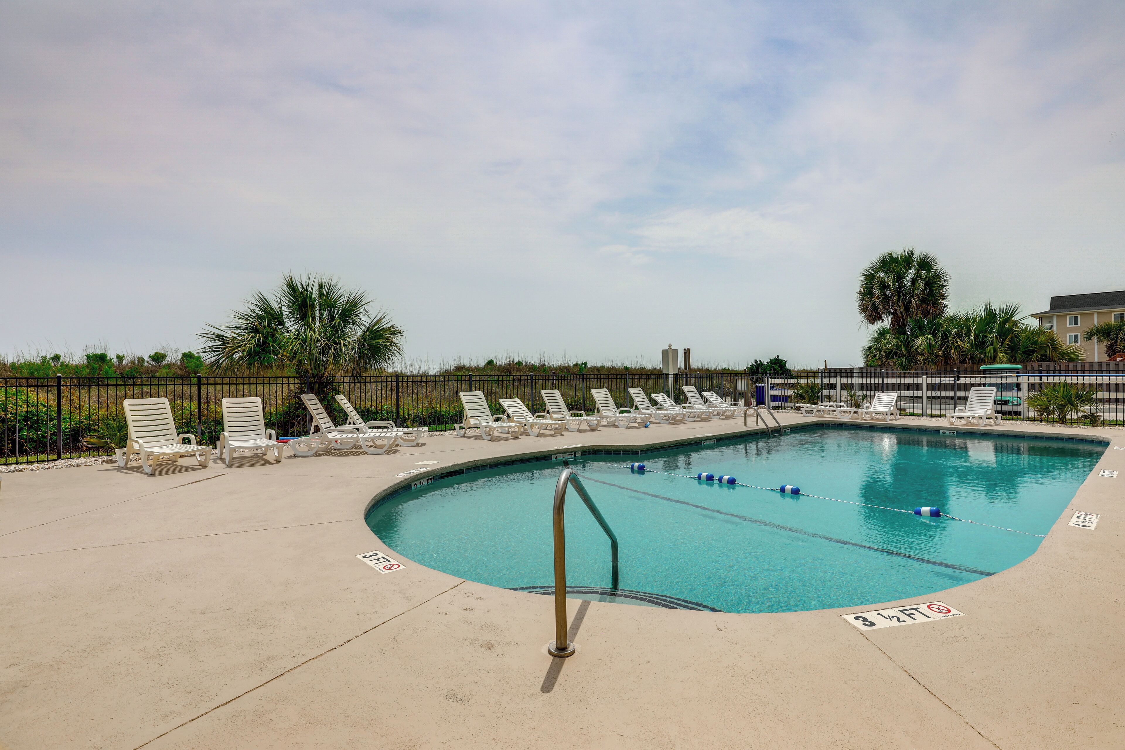 A swimming pool with lounge chairs and a metal ladder.