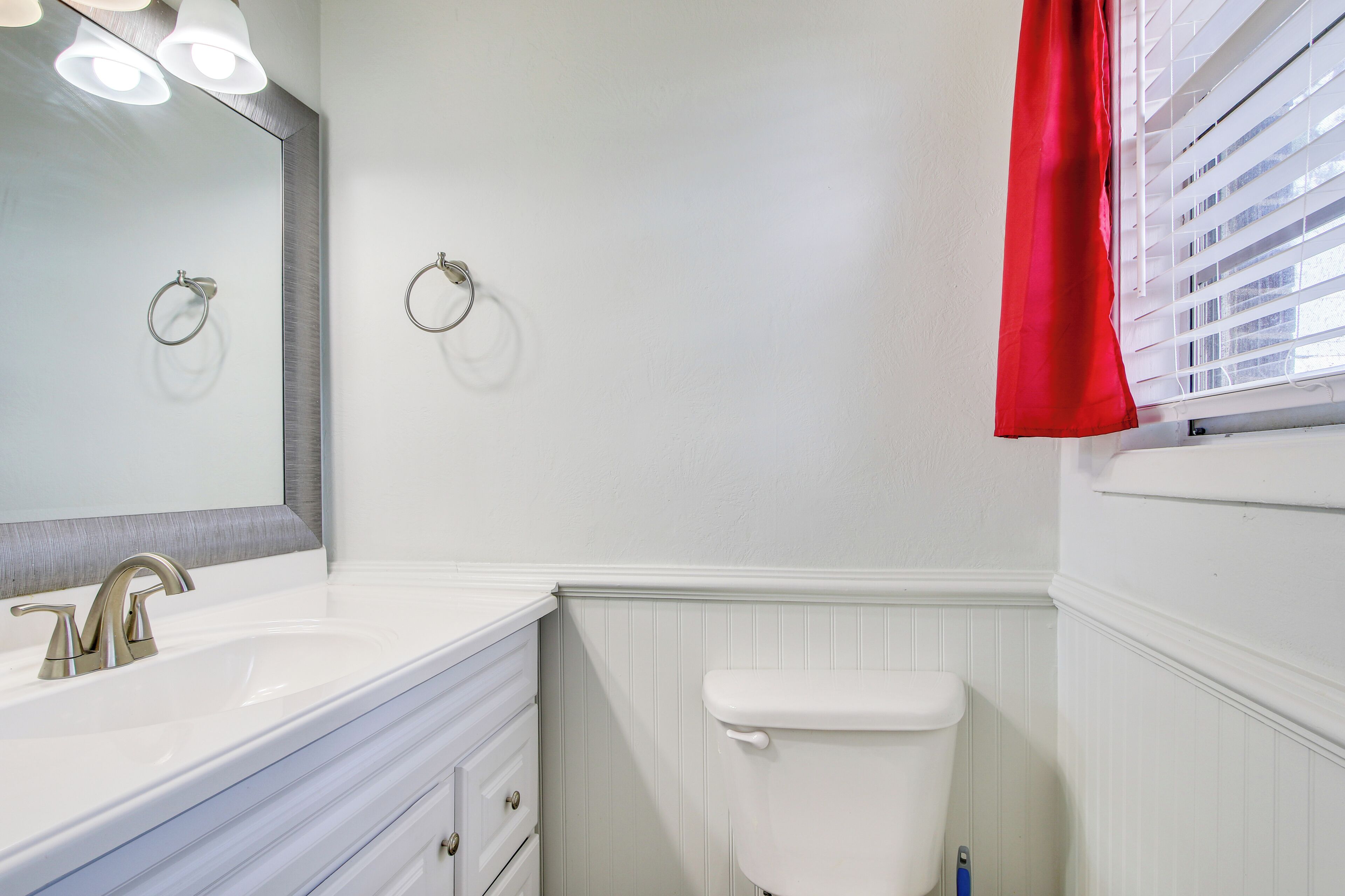 Baño con lavamanos, espejo y retrete blancos.