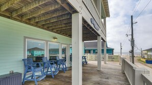 A wooden deck with blue chairs, a covered area with a railing, and a view of the beach. - 1 Block to Shore: Crystal Beach Gem, Deck & Views (Port Bolivar)