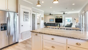 A modern kitchen with a large island, stainless steel appliances, pendant lighting, and a view into the living area. - 1 Block to Shore: Crystal Beach Gem, Deck & Views (Port Bolivar)
