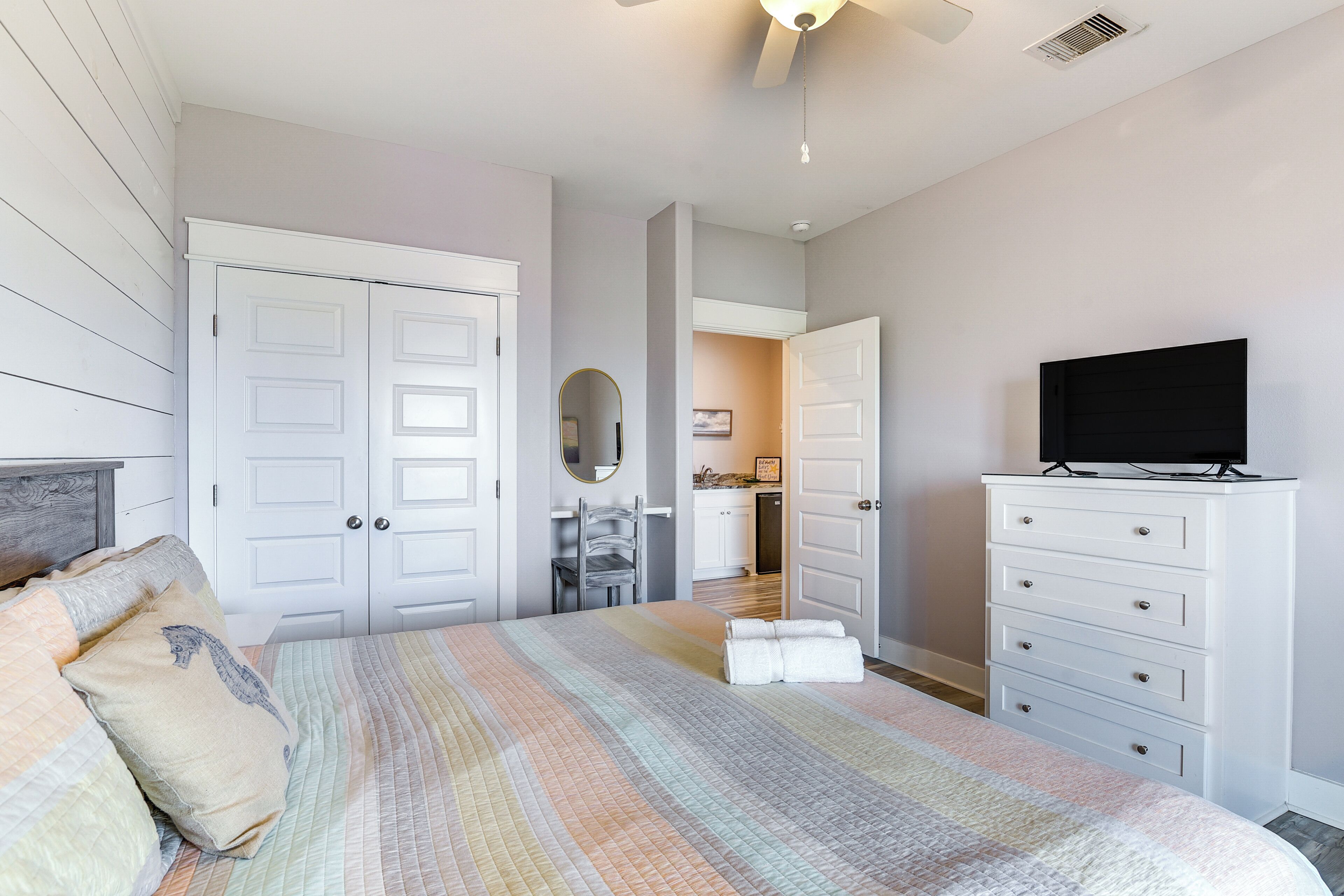 Un dormitorio con cama, cómoda, televisor y espejo.