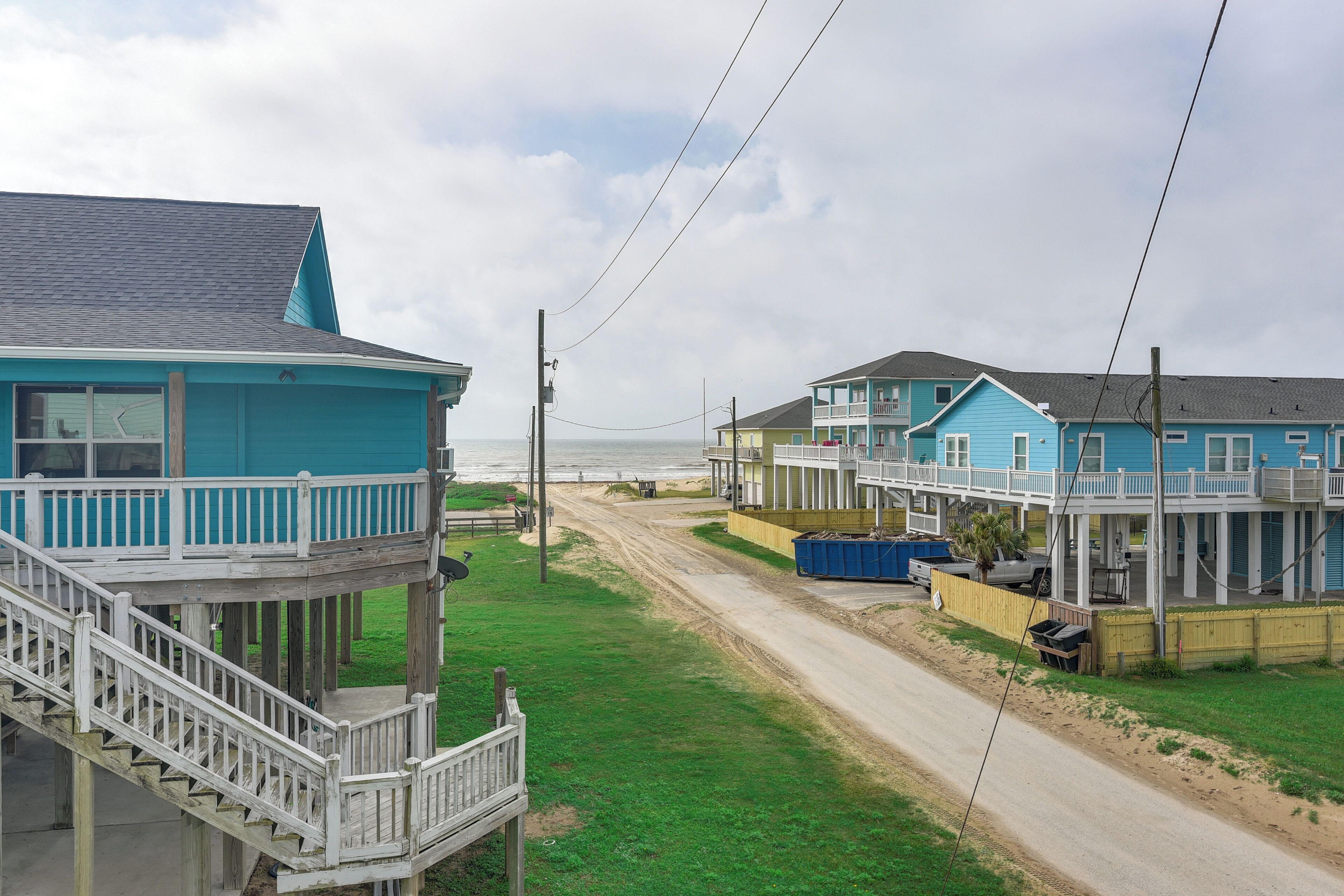 A coastal residential area with houses featuring balconies and a dirt road.