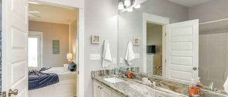 A bathroom with two sinks, a large mirror, and a door leading to another room.