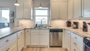 A modern kitchen with white cabinets, a stainless steel dishwasher, and a marble countertop. - 1 Block to Shore: Crystal Beach Gem, Deck & Views (Port Bolivar)