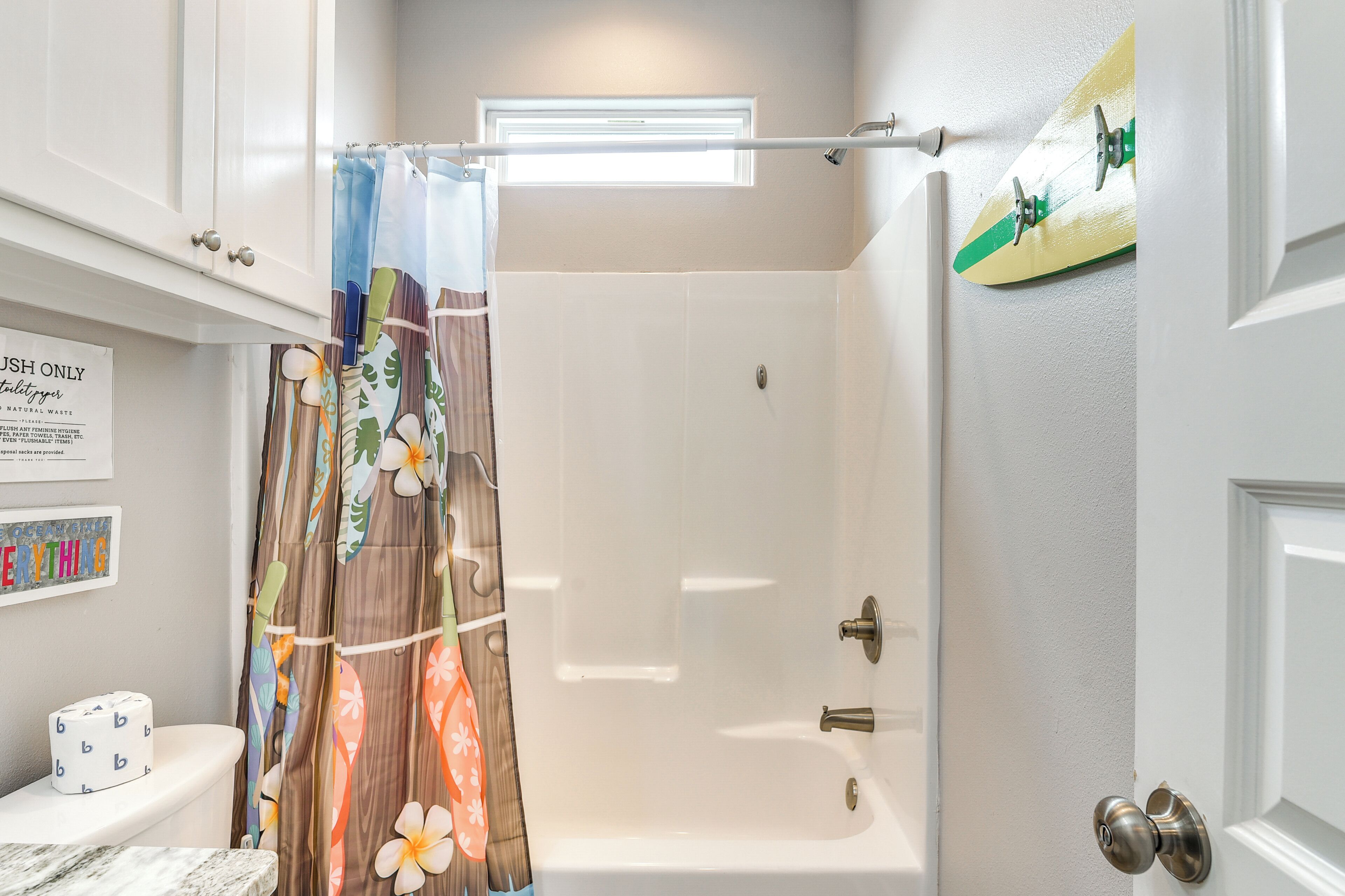 Ein Badezimmer mit Dusche, Toilette und Fenster.