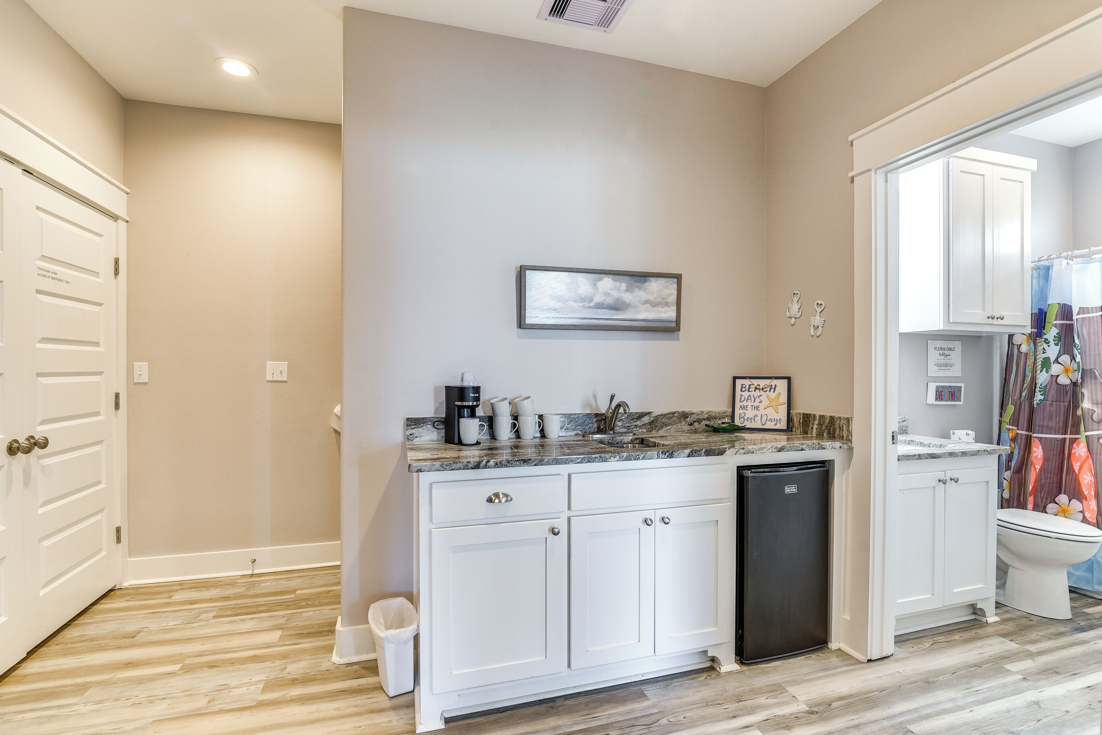 A kitchen with white cabinets, a black dishwasher, and a marble countertop.