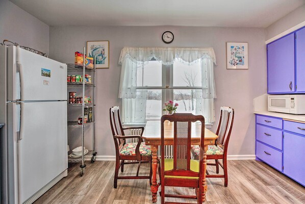 A kitchen with a refrigerator, microwave, and wooden dining table with chairs. - Cozy Cedarburg House - Walk to Historic Downtown! (Cedarburg)
