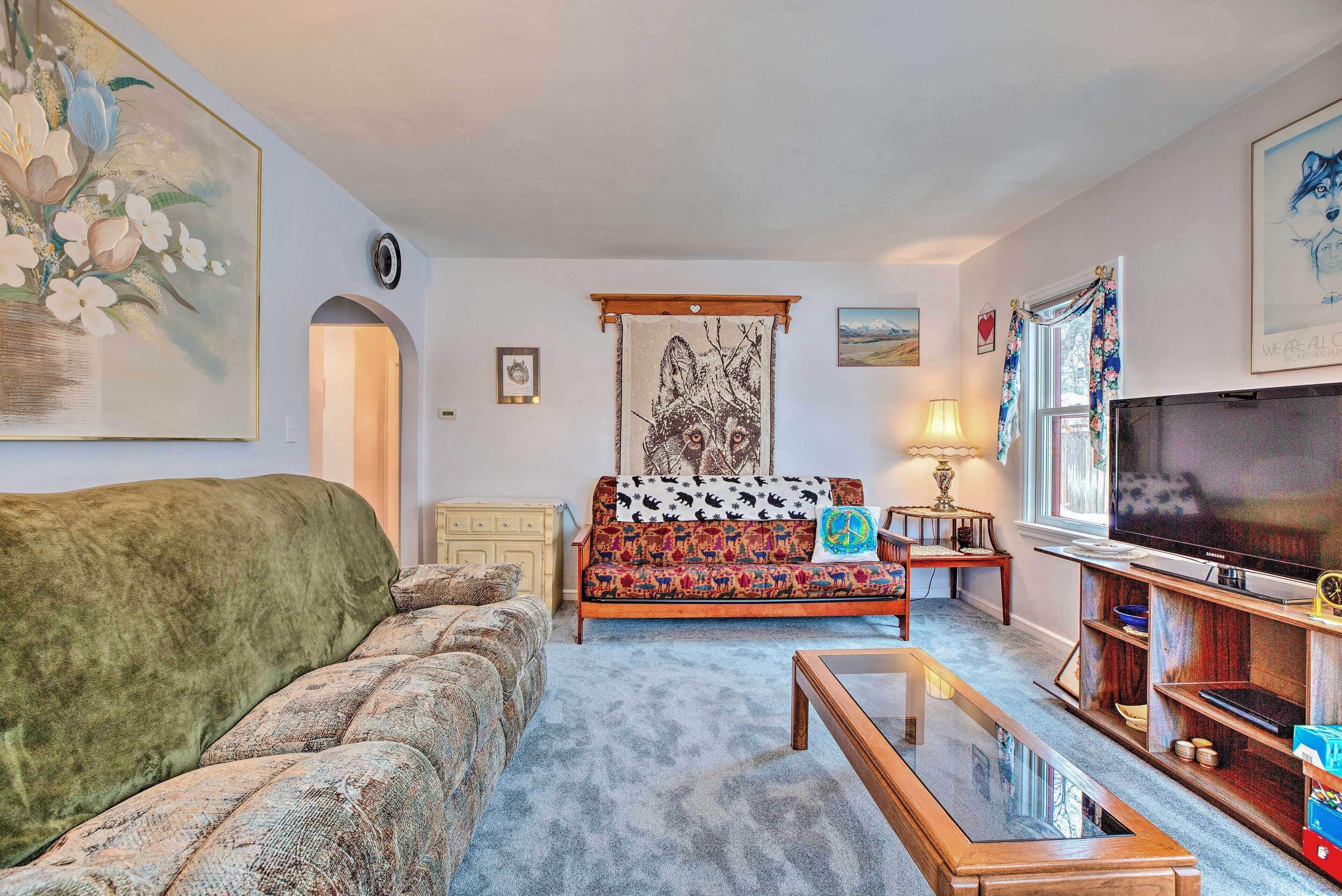 Ein Wohnzimmer mit einer Couch, einem Couchtisch, einem Fernseher und einem Gemälde an der Wand.