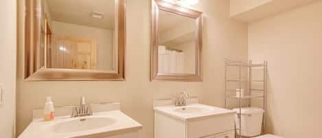 Une salle de bain avec deux lavabos, des toilettes et un espace douche.