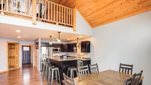 A spacious kitchen with a wooden island, dark cabinets, stainless steel appliances, and a dining area with a wooden table and chairs. - Pet Friendly Lake House: Waterfront w/ Boat Dock (Eagle River)