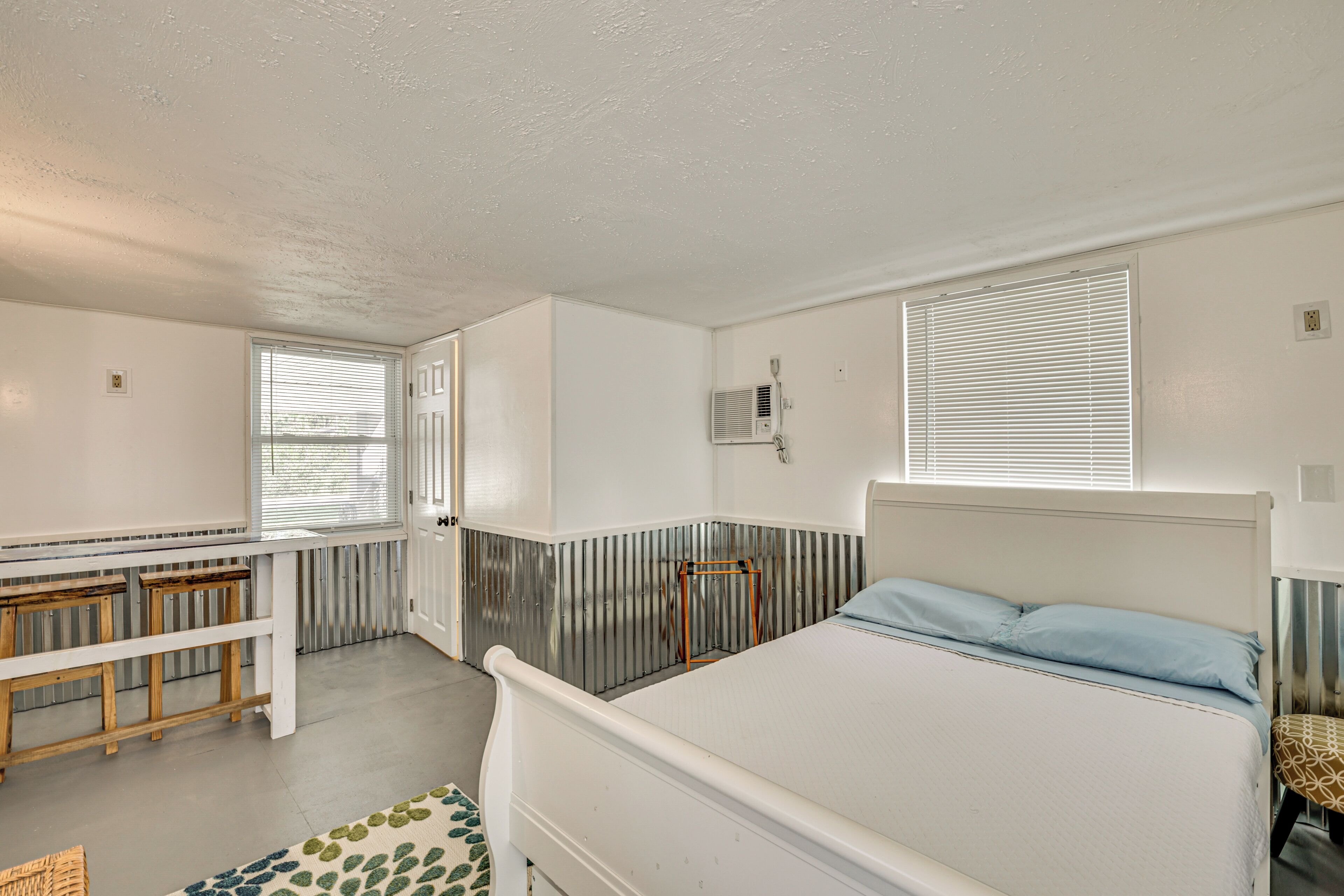 A bedroom with a bed, a bench, a radiator, and a window.