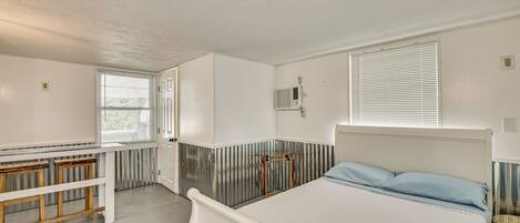 A bedroom with a bed, a bench, a radiator, and a window.