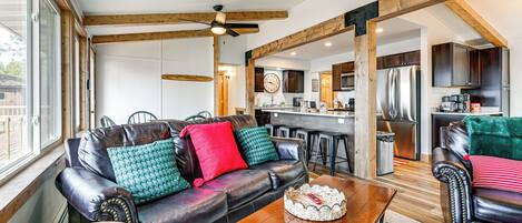 A spacious living area with a leather sofa, wooden coffee table, and a view of the kitchen in the background.