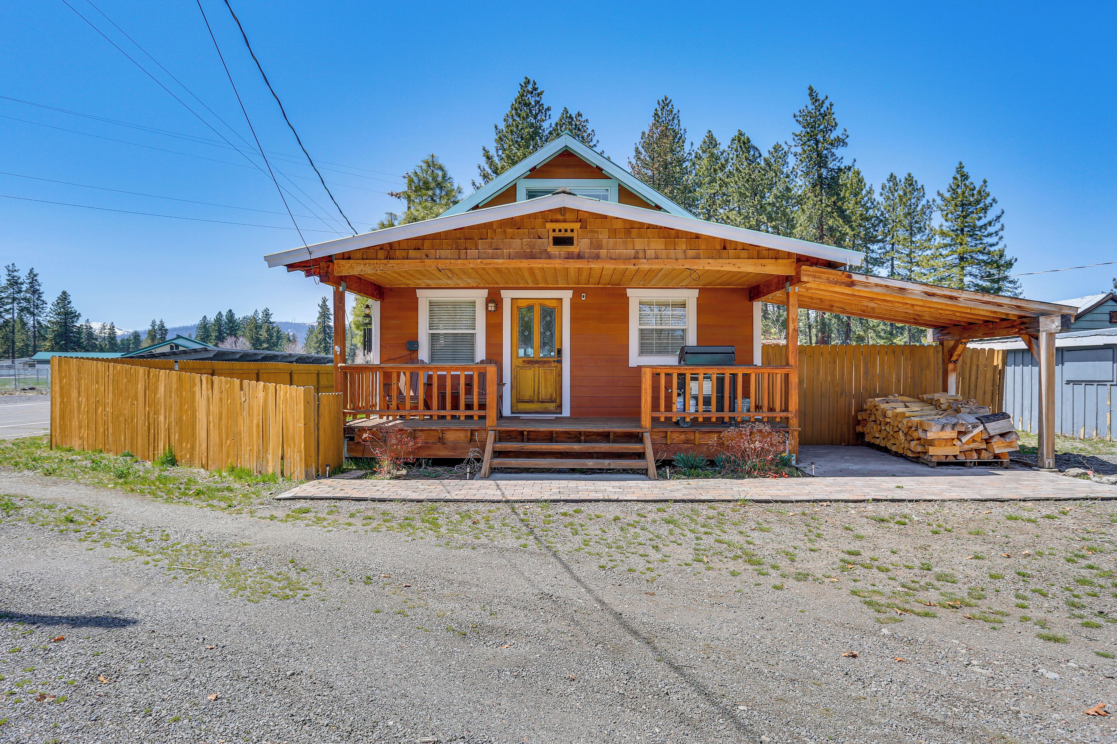 A wooden cabin with a porch, a front door, and a garage.