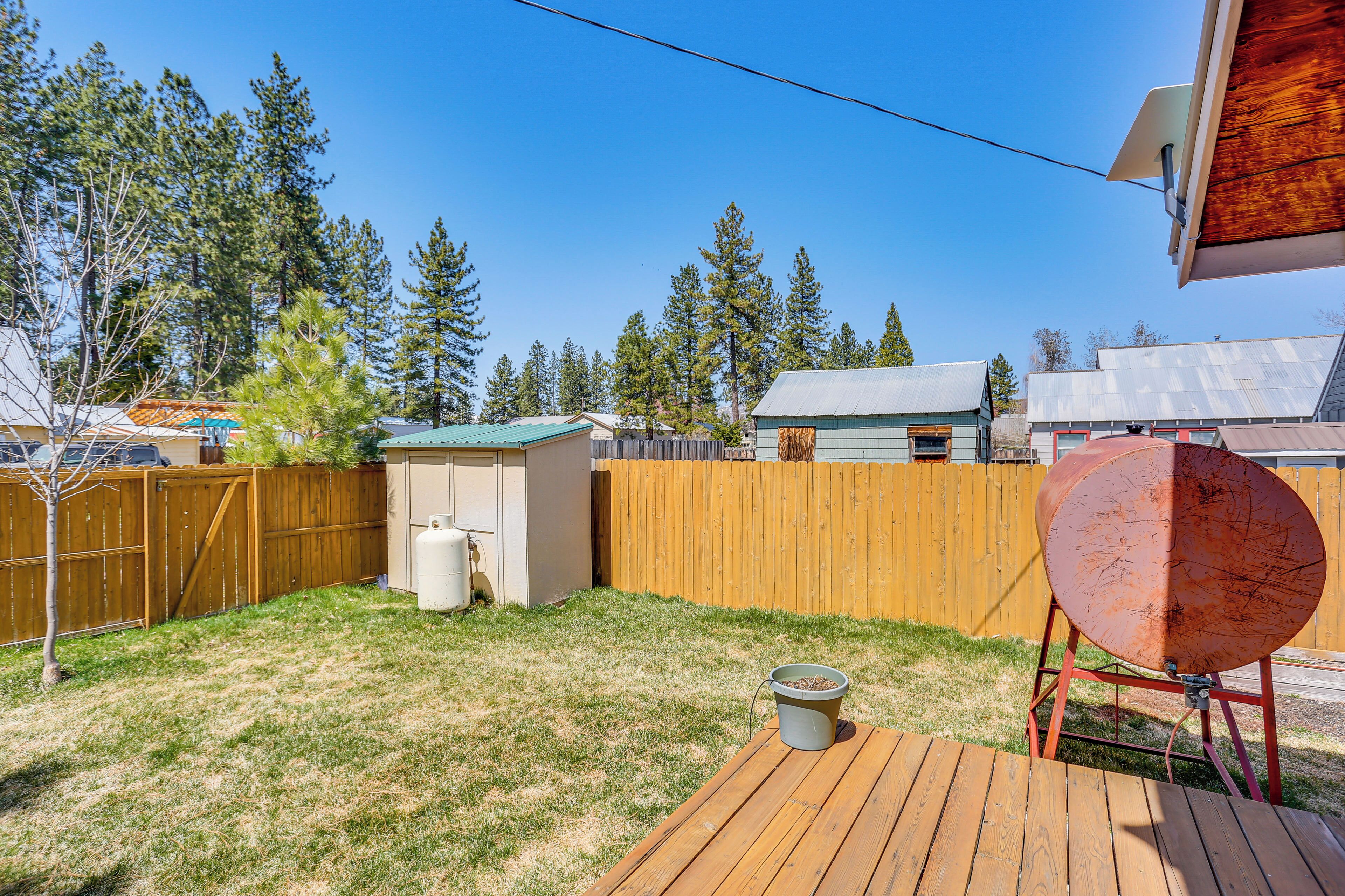 A backyard with a wooden deck, a barbecue grill, a shed, and a fence.