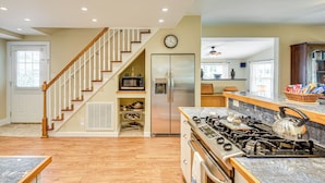 A kitchen with a wooden staircase, stainless steel appliances, and a granite countertop. - 1 Block to Crescent Lake: Charming Home w/ Porch! (Crescent City)