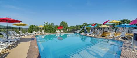 A swimming pool with lounge chairs and umbrellas.