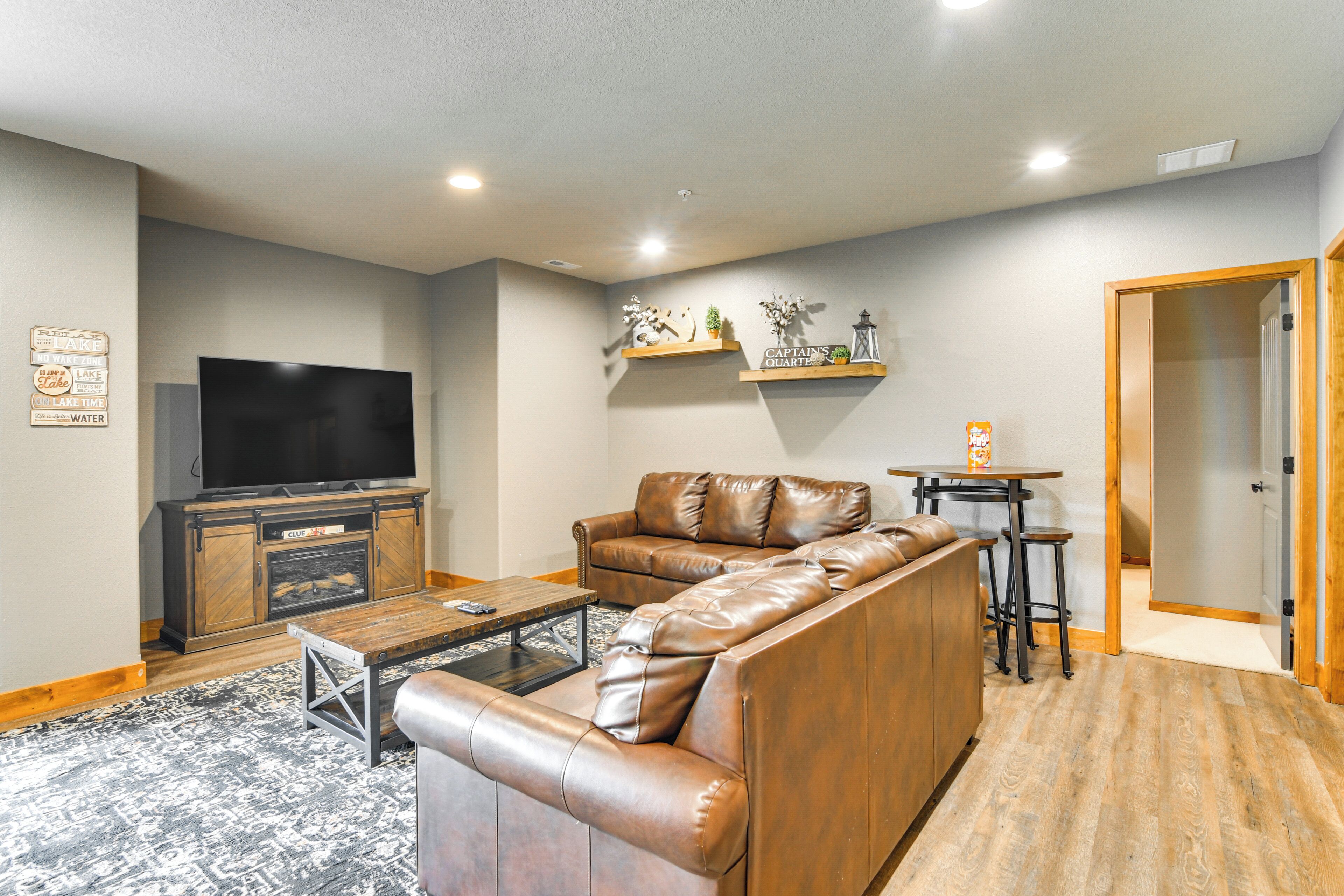 A living room with a leather sofa, a coffee table, a flat-screen TV, and a fireplace.