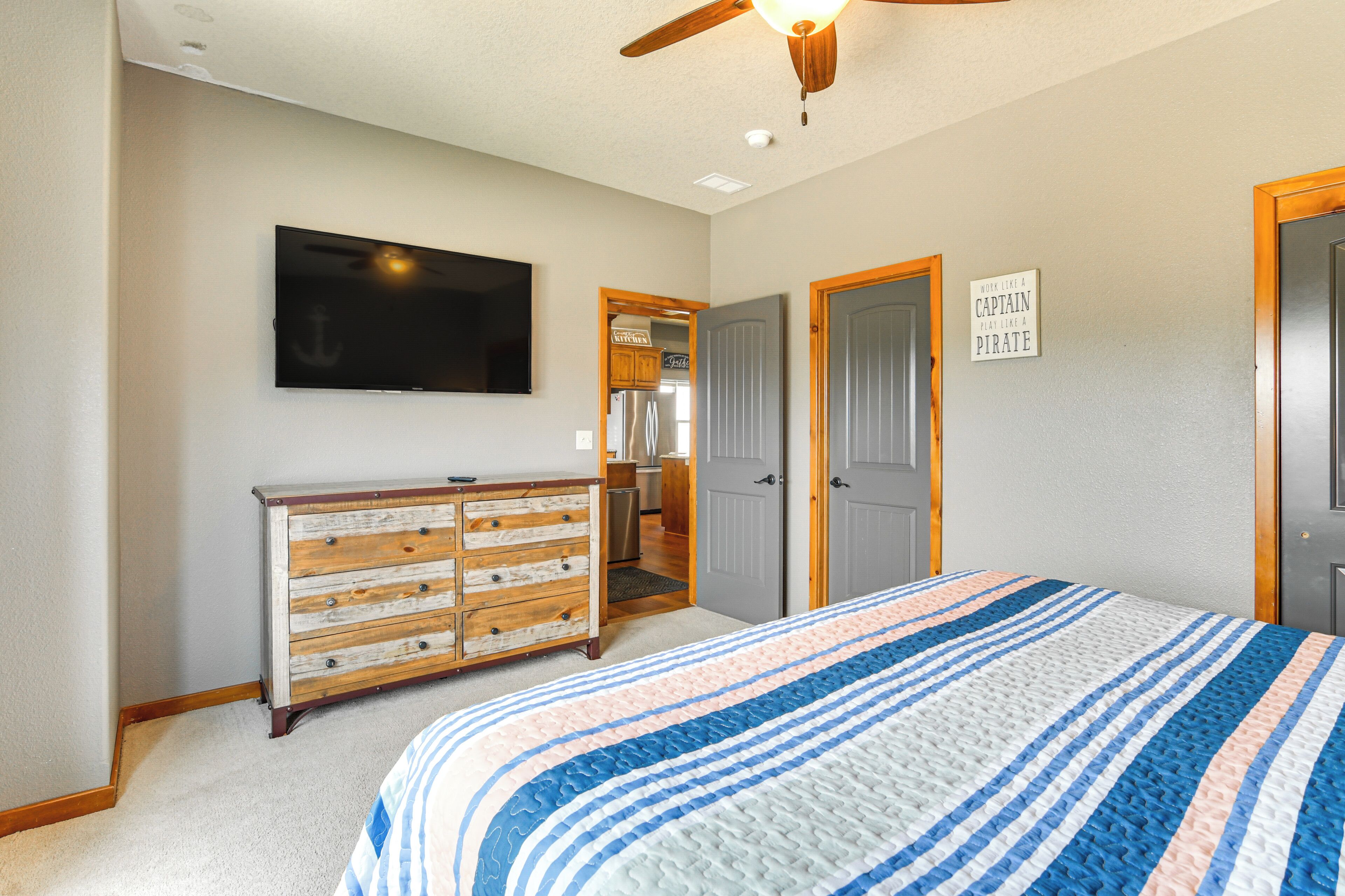 A bedroom with a bed, a dresser, a television, and a door with a sign.