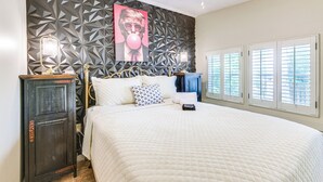A bedroom with a geometric-patterned headboard, a bed with a quilted white duvet, a nightstand with a lamp, and a wardrobe. - Private Dock + Porch: Lakefront Retreat in Cobb! (Cobb)