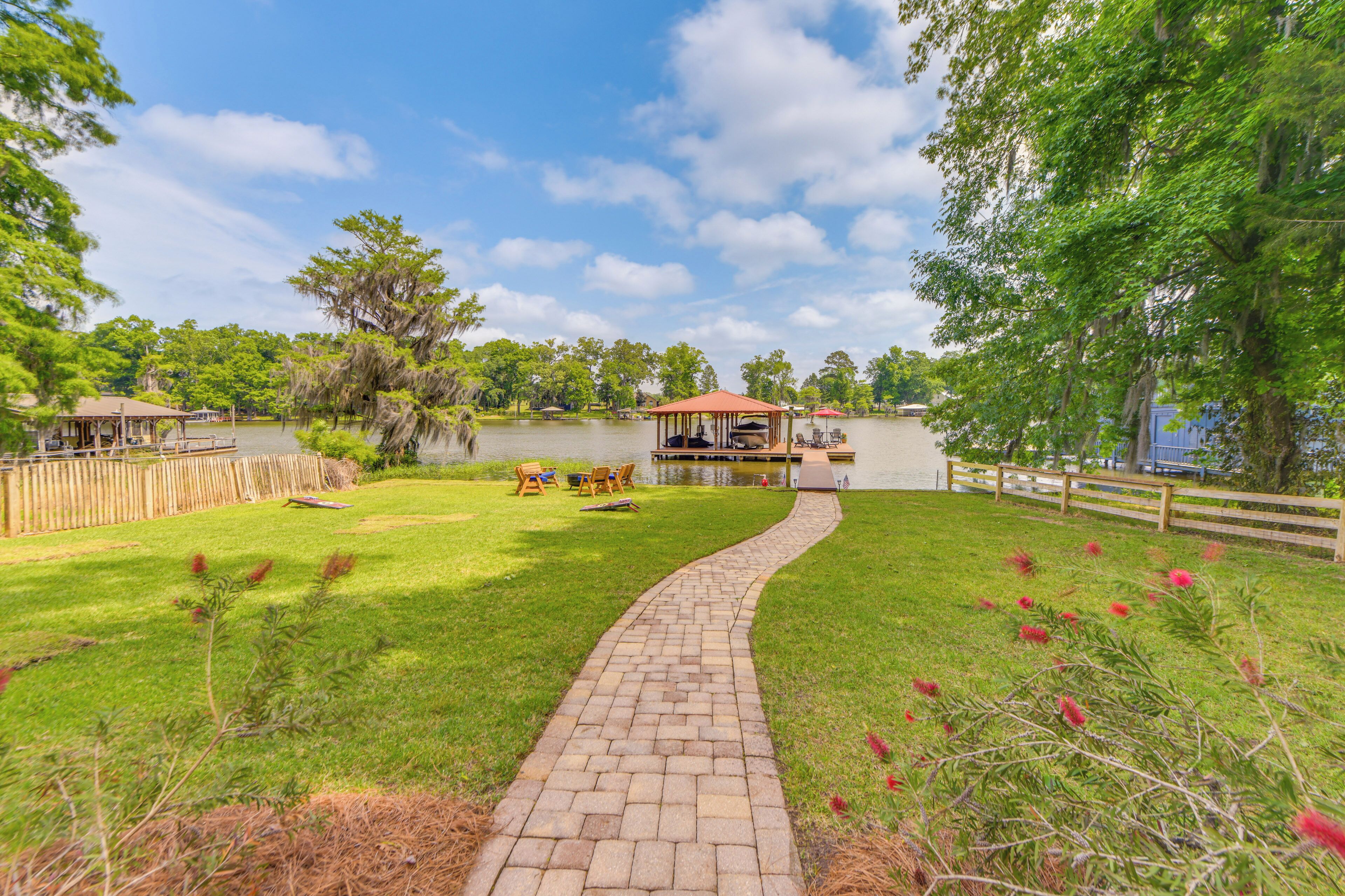 A backyard with a paved walkway, picnic tables, and a covered seating area by a lake.