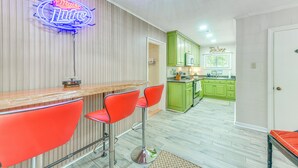A kitchen with green cabinets, a neon sign, and a bar area with red chairs. - Private Dock + Porch: Lakefront Retreat in Cobb! (Cobb)