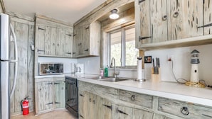 A kitchen with rustic wooden cabinets, a stainless steel sink, and a white countertop. - Private Beach: Waterfront Home on Lake Huron! (Greenbush)