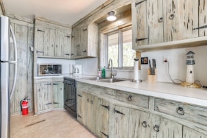 A kitchen with rustic wooden cabinets, a stainless steel sink, and a white countertop.