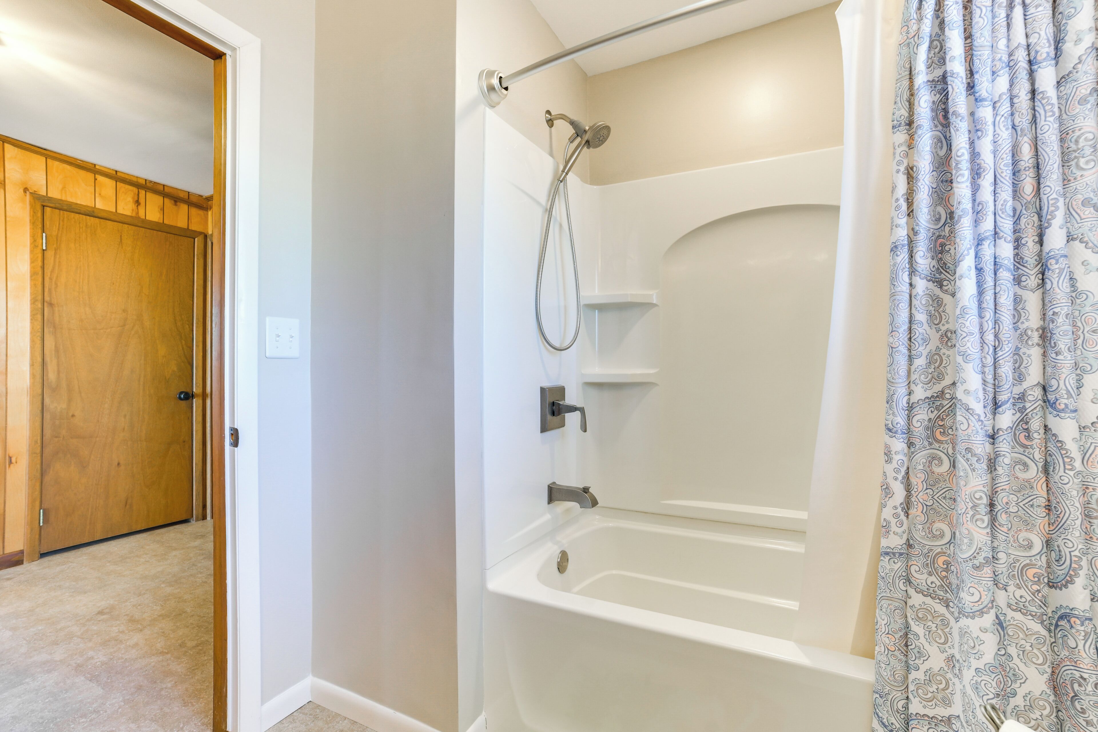 A bathroom with a walk-in shower, a bathtub, and a wooden door.