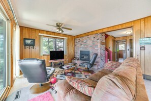 A cozy living room with a fireplace, leather chair, and a large sofa. - Private Beach: Waterfront Home on Lake Huron! (Greenbush)