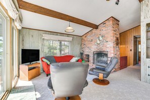 A living room with a fireplace, a television, and a red sofa. - Private Beach: Waterfront Home on Lake Huron! (Greenbush)