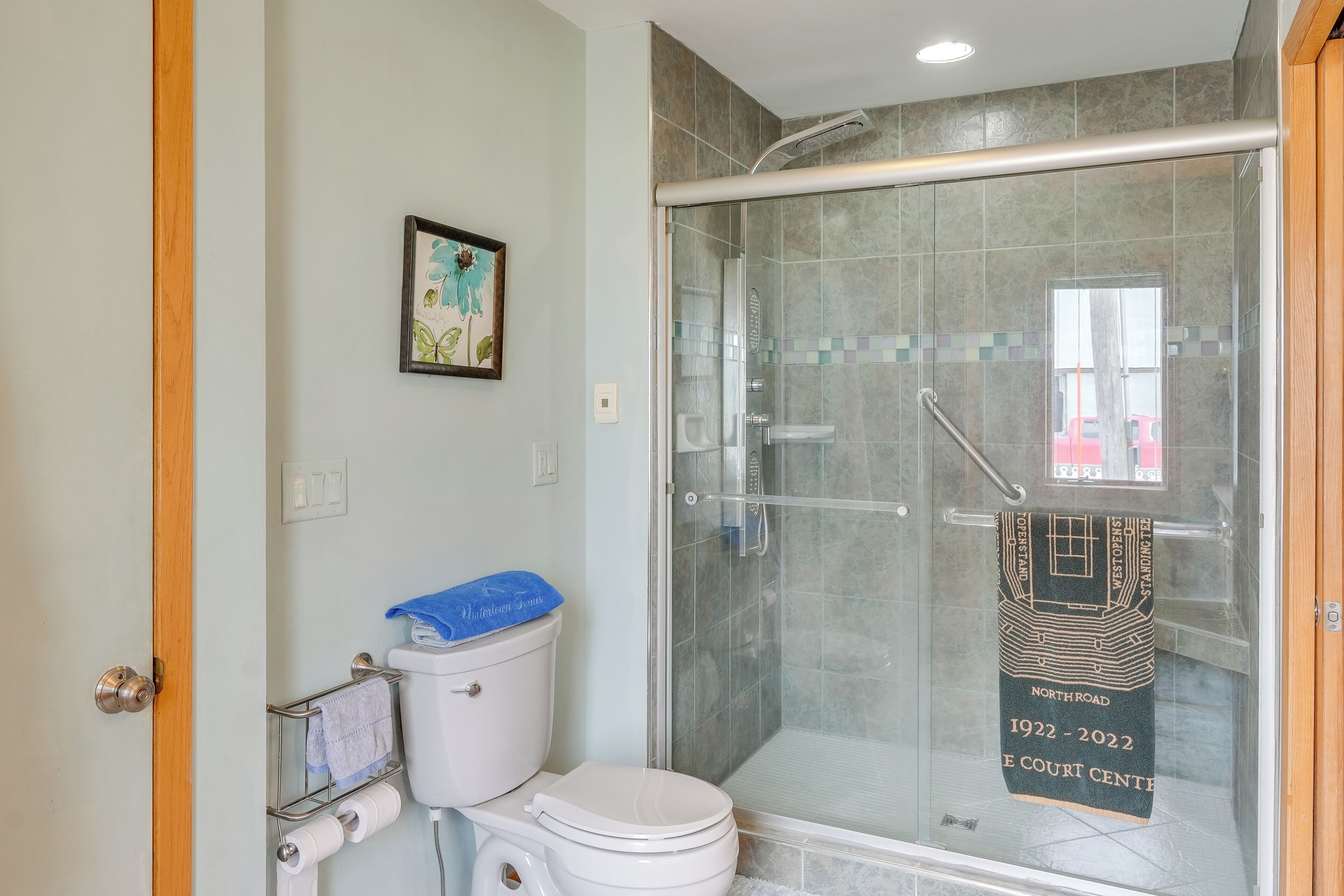 Une salle de bain dotée d’une douche à parois de verre, de toilettes et d’un porte-serviettes orné d’une serviette décorative.