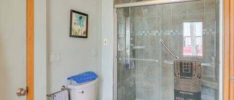 Une salle de bain dotée d’une douche à parois de verre, de toilettes et d’un porte-serviettes orné d’une serviette décorative.